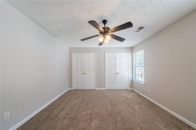 6509 Charter Way, Lithonia, GA 30058 - unfurnished bedroom featuring two closets, baseboards, carpet, a textured ceiling, and ceiling fan