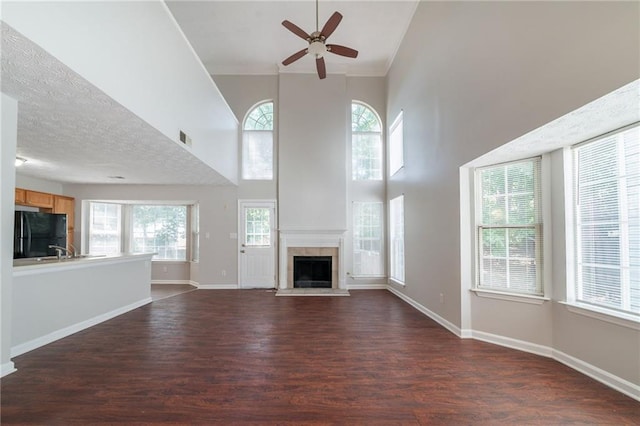 6509 Charter Way, Lithonia, GA 30058 - unfurnished living room featuring ceiling fan, dark wood-style floors, a towering ceiling, a tile fireplace, and baseboards