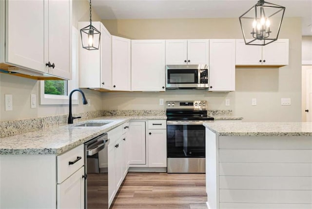 12 New St, Newnan, GA 30263 - kitchen featuring appliances with stainless steel finishes, a sink, light wood-style floors, white cabinetry, and light stone counters