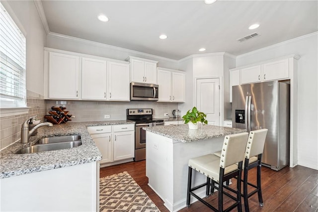 kitchen with a center island, dark hardwood / wood-style floors, sink, white cabinets, and stainless steel appliances