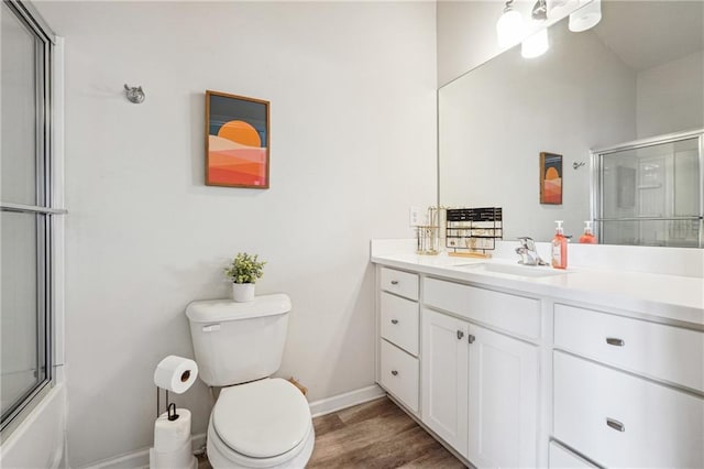 full bathroom featuring enclosed tub / shower combo, hardwood / wood-style floors, vanity, and toilet