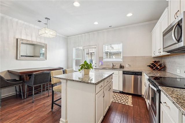 kitchen featuring pendant lighting, white cabinets, appliances with stainless steel finishes, dark hardwood / wood-style floors, and a center island