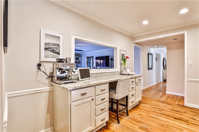 interior space featuring ornamental molding, built in desk, and light wood-type flooring