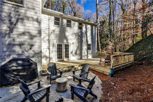 rear view of house featuring a wooden deck, french doors, and an outdoor fire pit