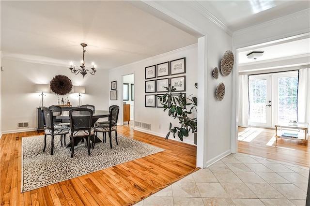 tiled dining area with crown molding, a chandelier, and french doors