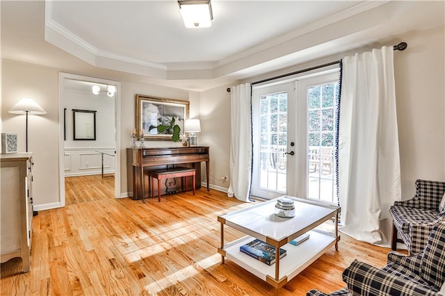 sitting room featuring french doors, crown molding, light wood-type flooring, and a tray ceiling