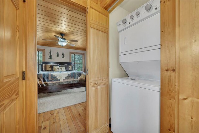 laundry area with light hardwood / wood-style floors, wood ceiling, stacked washer / drying machine, and ceiling fan