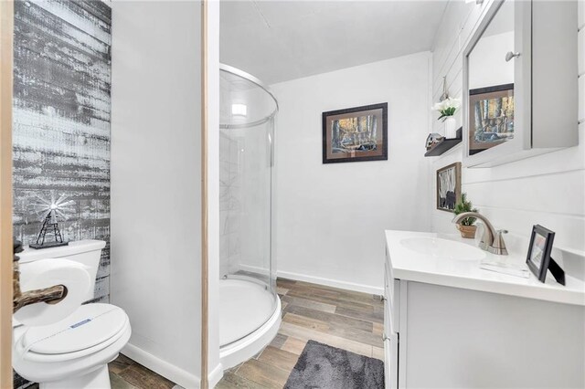 bathroom featuring vanity, hardwood / wood-style floors, a shower with shower door, and toilet