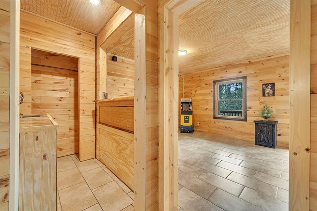 corridor with wood ceiling, light tile patterned floors, and wood walls