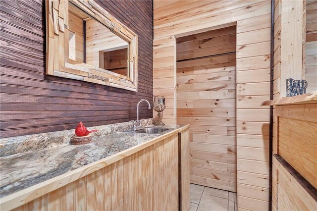 bathroom featuring sink, wooden walls, and tile patterned floors