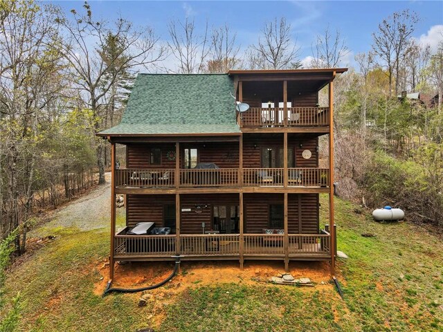 rear view of house with a wooden deck and a lawn