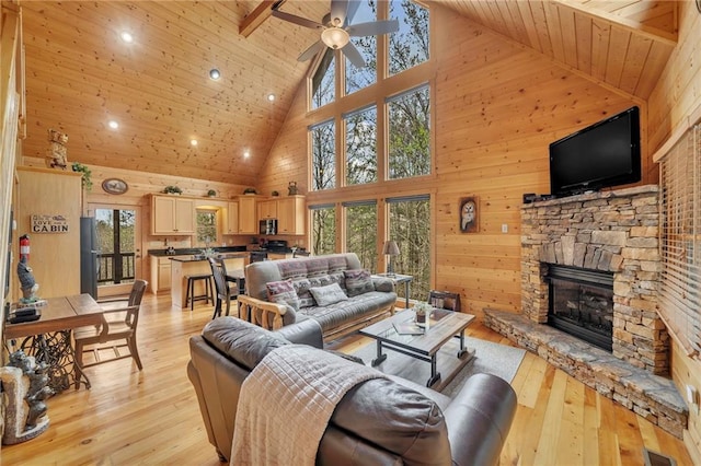 living room featuring wood ceiling, high vaulted ceiling, light wood-type flooring, and a stone fireplace