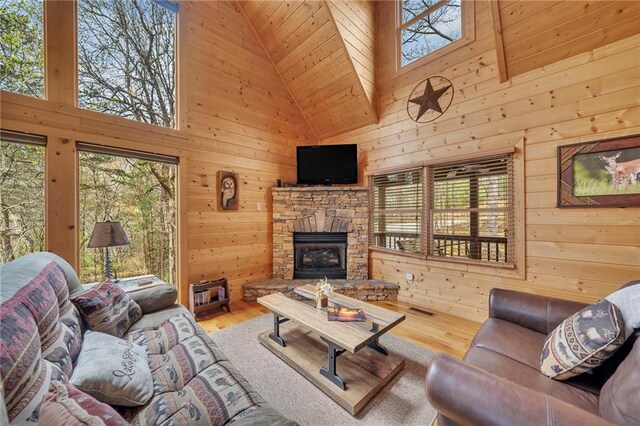 living room featuring high vaulted ceiling, wood-type flooring, a fireplace, and wood walls