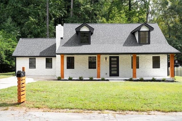 view of front of home featuring a front yard, covered porch, roof with shingles, and a chimney