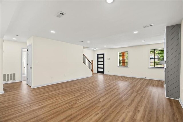 unfurnished living room featuring light wood-style flooring, stairs, visible vents, and recessed lighting