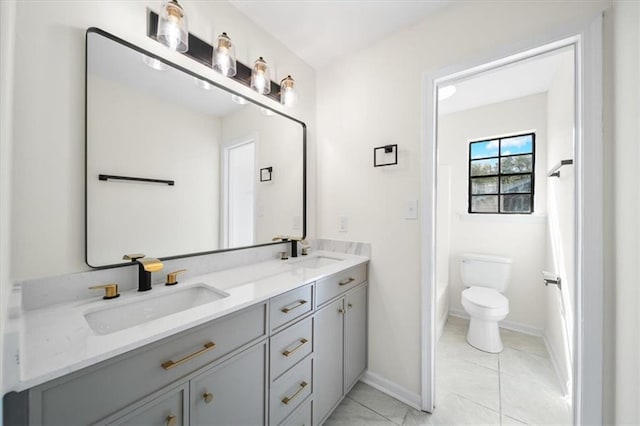 bathroom with toilet, double vanity, baseboards, and a sink