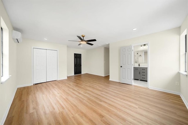 unfurnished bedroom featuring light wood-style floors, recessed lighting, baseboards, and a wall mounted air conditioner