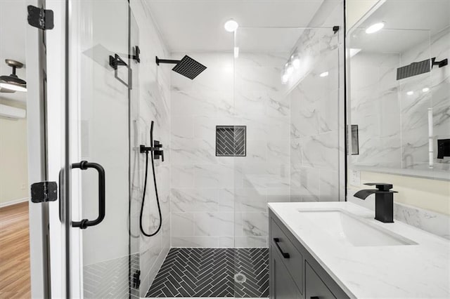 full bathroom featuring wood finished floors, a marble finish shower, and vanity