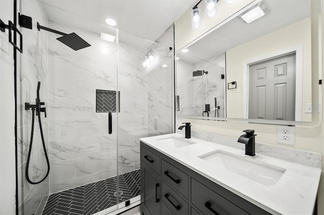 full bathroom featuring a sink, a marble finish shower, and double vanity