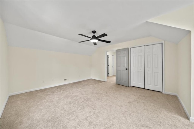 unfurnished bedroom featuring carpet floors, ceiling fan, baseboards, and lofted ceiling