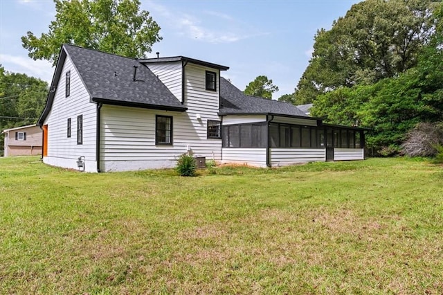 back of house featuring a shingled roof, a lawn, and a sunroom