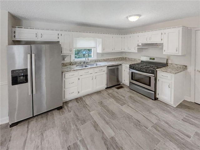 kitchen with sink, stainless steel appliances, white cabinetry, and a textured ceiling