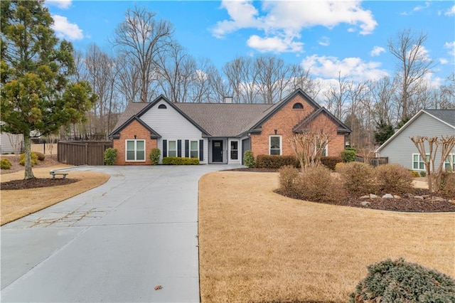 single story home featuring concrete driveway, brick siding, a front yard, and fence