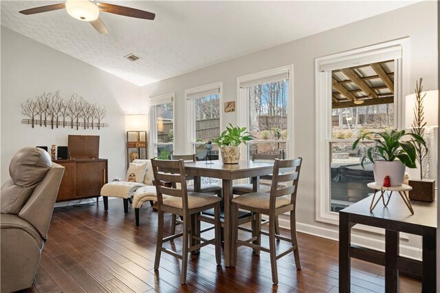 dining space featuring dark wood-style flooring, visible vents, ceiling fan, and a textured ceiling