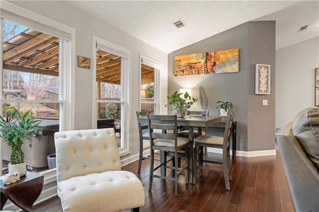 dining room featuring vaulted ceiling, dark wood finished floors, visible vents, and baseboards