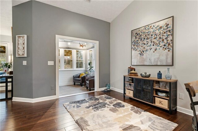 interior space featuring lofted ceiling, baseboards, dark wood finished floors, and a chandelier