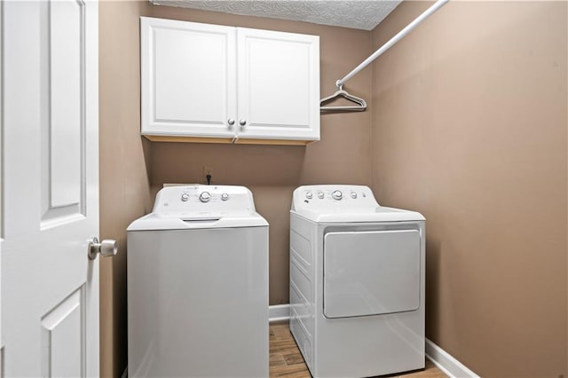 laundry room featuring wood finished floors, cabinet space, baseboards, and separate washer and dryer