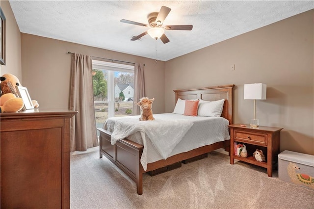 bedroom with a ceiling fan, a textured ceiling, and light colored carpet