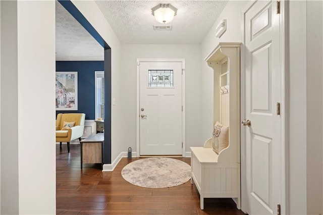 foyer entrance with a textured ceiling, wood-type flooring, visible vents, and baseboards