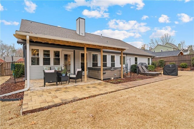 back of property with a fenced backyard, a patio, a hot tub, and an outdoor hangout area