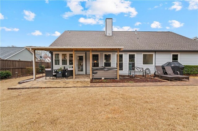 back of house featuring a hot tub, a chimney, roof with shingles, fence, and a patio area