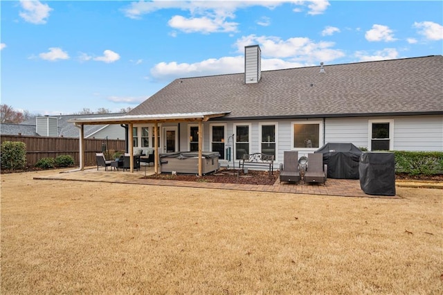 back of property with a hot tub, a patio, a chimney, fence, and a yard