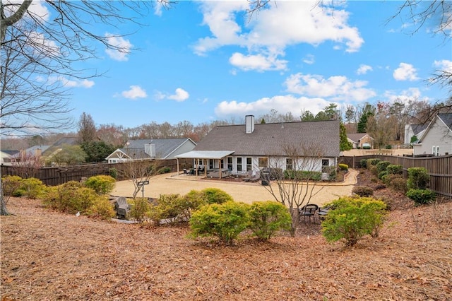 rear view of property featuring a chimney, a patio area, and a fenced backyard