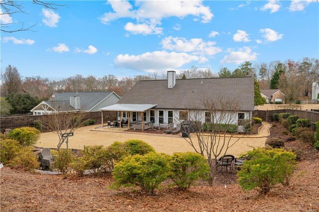 rear view of property with a patio, a chimney, and a fenced backyard