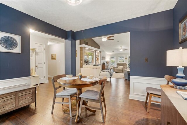 dining room featuring lofted ceiling, a wainscoted wall, a decorative wall, and wood finished floors