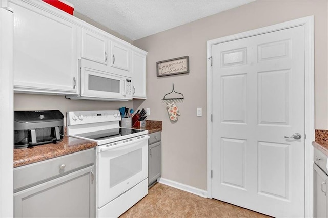 kitchen featuring white cabinetry, dark stone countertops, white appliances, and a textured ceiling