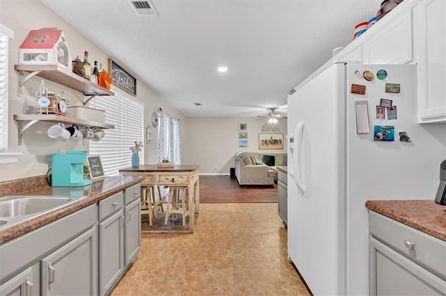 kitchen with white cabinets, ceiling fan, white fridge, and sink