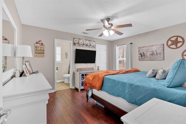 bedroom with a textured ceiling, ceiling fan, ensuite bathroom, and dark hardwood / wood-style floors