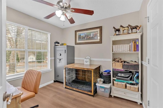 home office with light wood-type flooring, plenty of natural light, and ceiling fan