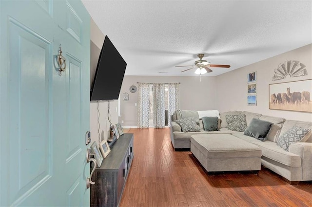 living room with a textured ceiling, ceiling fan, and dark hardwood / wood-style floors