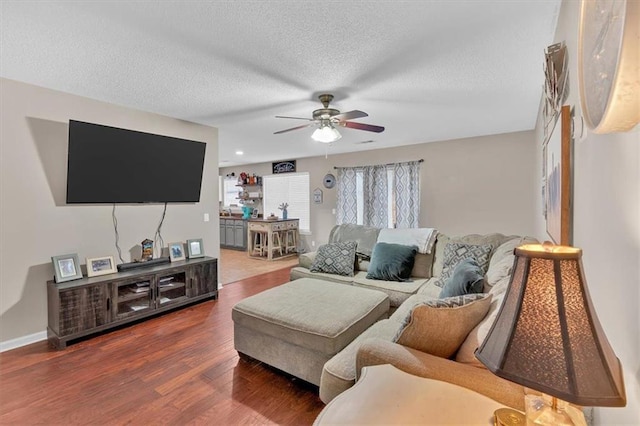 living room featuring ceiling fan, dark wood-type flooring, and a textured ceiling