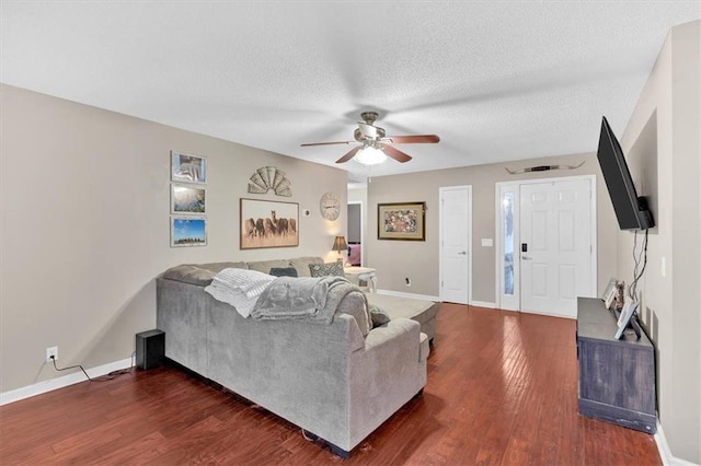 living room with a textured ceiling, dark hardwood / wood-style floors, and ceiling fan