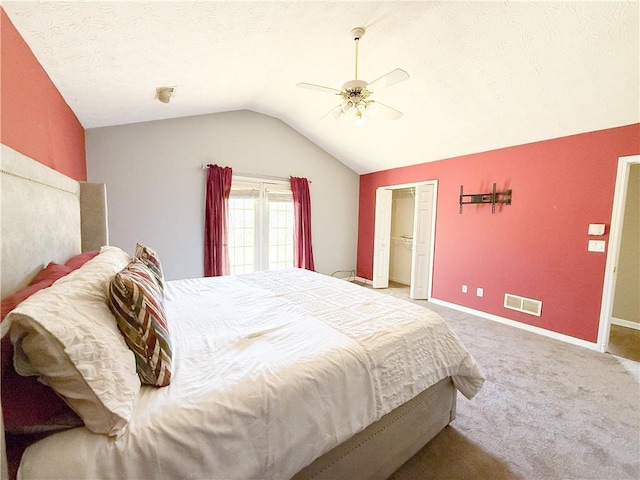 carpeted bedroom featuring a textured ceiling, vaulted ceiling, and ceiling fan