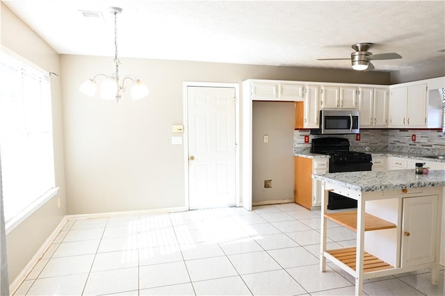 kitchen featuring tasteful backsplash, white cabinetry, hanging light fixtures, black gas stove, and light stone countertops