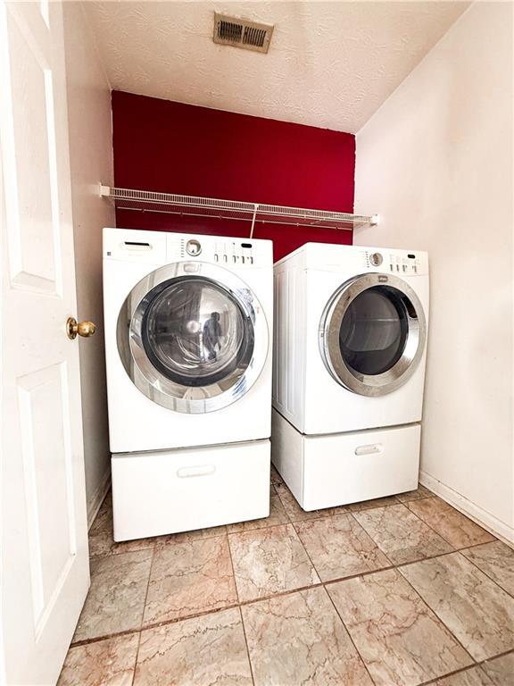 laundry room featuring washer and dryer and a textured ceiling