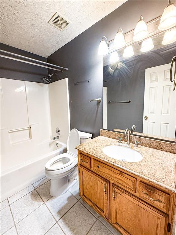 full bathroom with toilet, a textured ceiling, shower / washtub combination, vanity, and tile patterned flooring